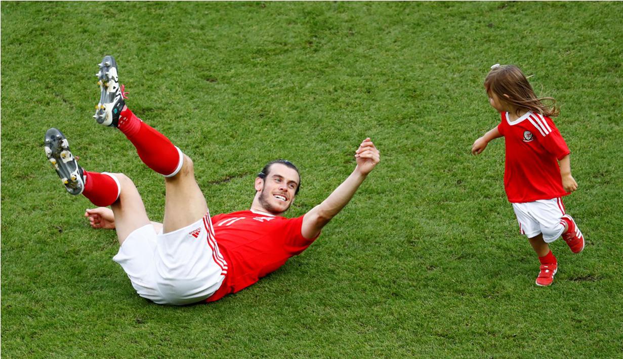 Pemain Wales, Gareth Bale, bercengkerama dengan putrinya setelah menang melawan Irlandia Utara pada laga 16 besar Piala Eropa 2016 di Parc des Princes, Paris, Sabtu (25/6/2016) malam WIB. (Reuters/Christian Hartmann)