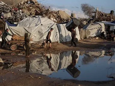 Seorang pria Palestina yang terlantar menarik gerobak setelah hujan deras di kota Jabalia, Jalur Gaza utara, pada Selasa 25 November 2025. Hujan deras yang mengguyur wilayah di Jalur Gaza, pada Selasa (25/11/2025) menyebabkan sejumlah lokasi penampungan pengungsi terendam banjir. (Omar AL-QATTAA/AFP)