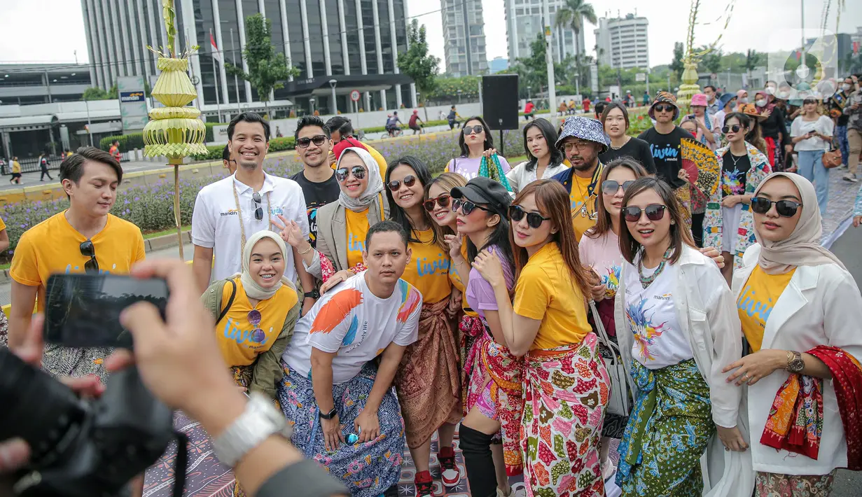 Sejumlah orang yang mengenakan batik berpose di catwalk Jalan Jenderal Sudirman, Jakarta, Minggu (2/10/2022). Kegiatan yang diikuti ratusan orang ini diselenggarakan oleh Bank Mandiri untuk menyambut Hari Batik Nasional yang jatuh setiap tanggal 2 Oktober 2022. (Liputan6.com/Faizal Fanani)