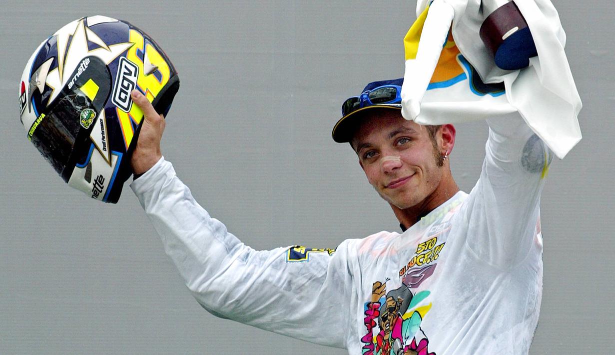 Pebalap MotoGP asal Italia, Valentino Rossi mengangkat helm merayakan gelar juara di Sirkuit Sepang, Malaysia, Minggu (12/10/2003). (AFP/Jimin Lai)