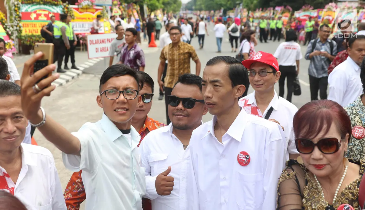 Warga berebut foto bersama dengan Reza Sri Mulyadi di sekitar lokasi akad nikah Kahiyang Ayu dengan Bobby Nasution, Solo, Rabu (8/11). Relawan asal Jakarta itu berhasil menipu warga dengan wajahnya yang mirip Presiden Jokowi. (Liputan6.com/Angga Yuniar)