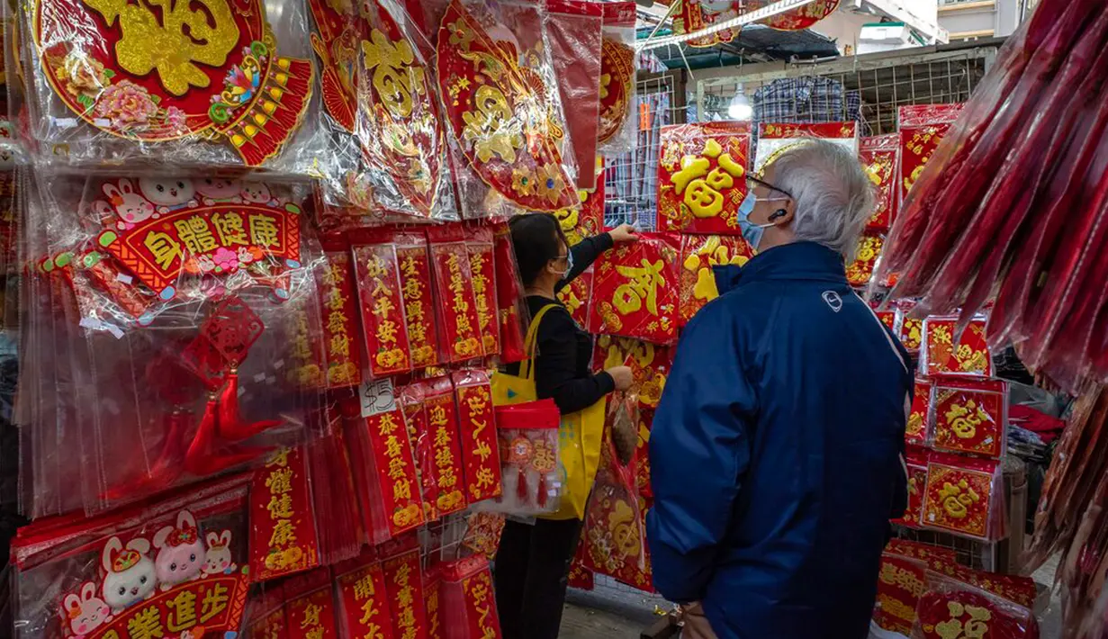 Para pembeli melihat dekorasi Tahun Baru Imlek yang dijual di sebuah kios pinggir jalan di Distrik Sham Shui Po, Hong Kong, 18 Januari 2023. Tahun Baru Imlek 2023 yang disebut Tahun Kelinci akan jatuh pada tanggal 22 Januari. (AP Photo/Anthony Kwan)
