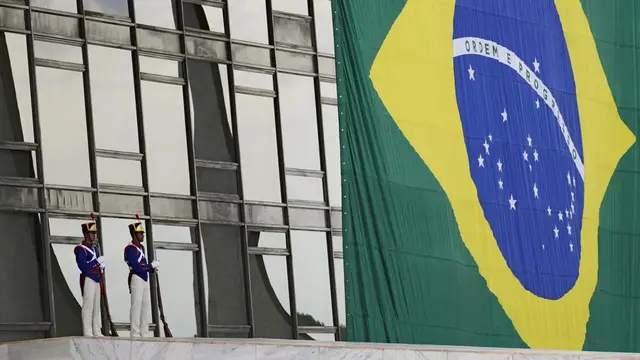Tentara berjaga di samping bendera Brasil di jalan di Istana Planalto di Brasilia, Brasil, Senin, 31 Oktober 2022, pagi setelah pemilihan kembali mantan Presiden Brasil Luiz Inacio Lula da Silva. (Foto AP/Eraldo Peres)