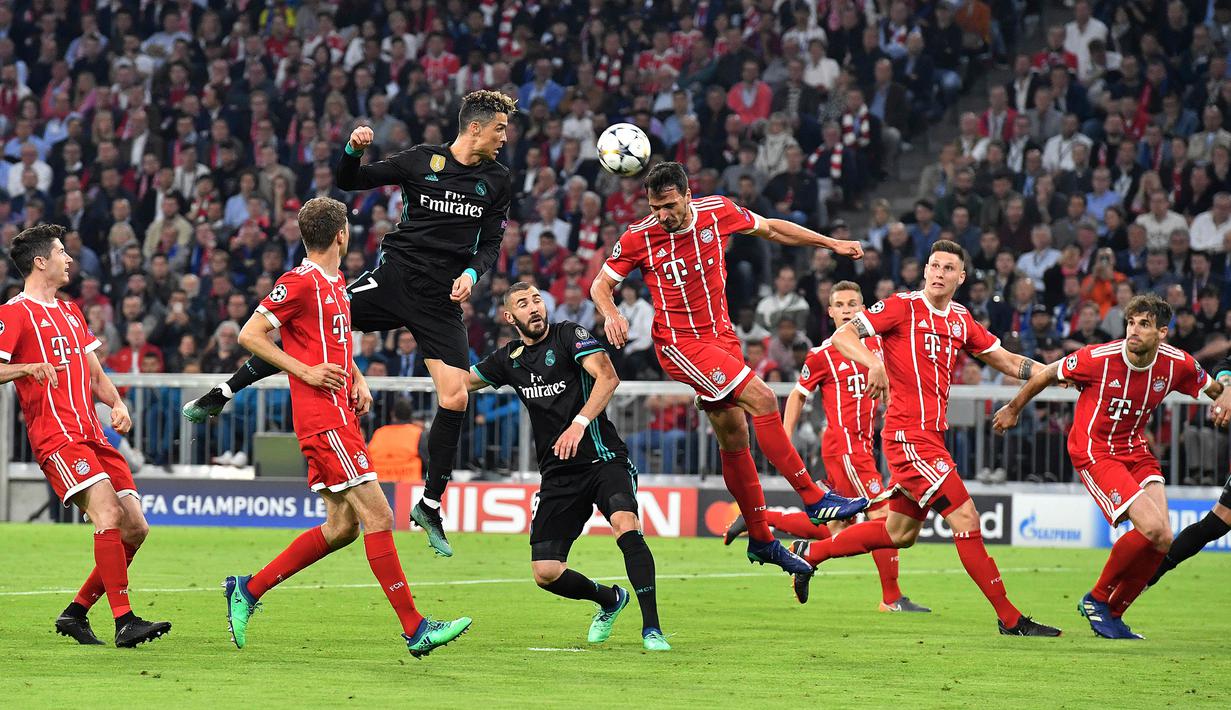 Megabintang Real Madrid, Cristiano Ronaldo menyundul bola dibayangi pemain Bayern Munchen pada leg pertama semifinal Liga Champions di Allianz Arena, Rabu (25/4). Real Madrid berhasil menumbangkan Bayern Munchen 2-1. (AP/Kerstin Joensson)