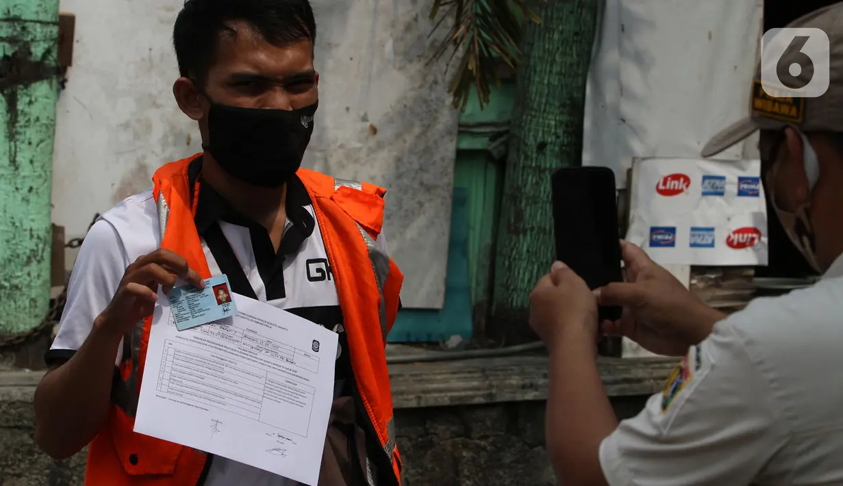 Petugas Satpol PP (kanan) memotret warga pelanggar PSBB yang terjaring razia masker di Jalan Tanjung Duren Raya, Jakarta, Jumat (11/9/2020). Petugas Satpol PP gencar melakukan razia masker menyusul kasus COVID-19 di DKI Jakarta yang terus meningkat. (merdeka.com/Imam Buhori)