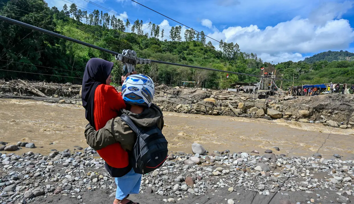 Terputusnya akses jalan dan jembatan membuat warga Kecamatan Ketol bertahan hidup menghadapi keterisolasian dengan menggunakan tali sling untuk melintasi sungai demi menjalani aktivitas sehari-hari. Tampak dalam foto, warga menggunakan tali untuk menyeberangi sungai setelah banjir bandang yang menghancurkan desa-desa di sekitarnya di Ketol, provinsi Aceh, pada Selasa 6 Januari 2026. (CHAIDEER MAHYUDDIN/AFP)