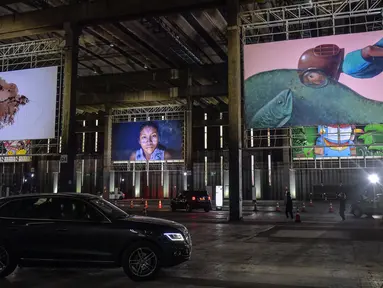 Orang-orang mengunjungi pameran seni dengan mengendarai mobil mereka melintasi gudang yang memajang lukisan dan foto di Sao Paulo pada 30 Juli 2020. Dengan galeri-galeri dan museum ditutup akibat pandemi virus corona, pemilik galeri seni Brasil meresmikan pameran drive-thru. (NELSON ALMEIDA/AFP)