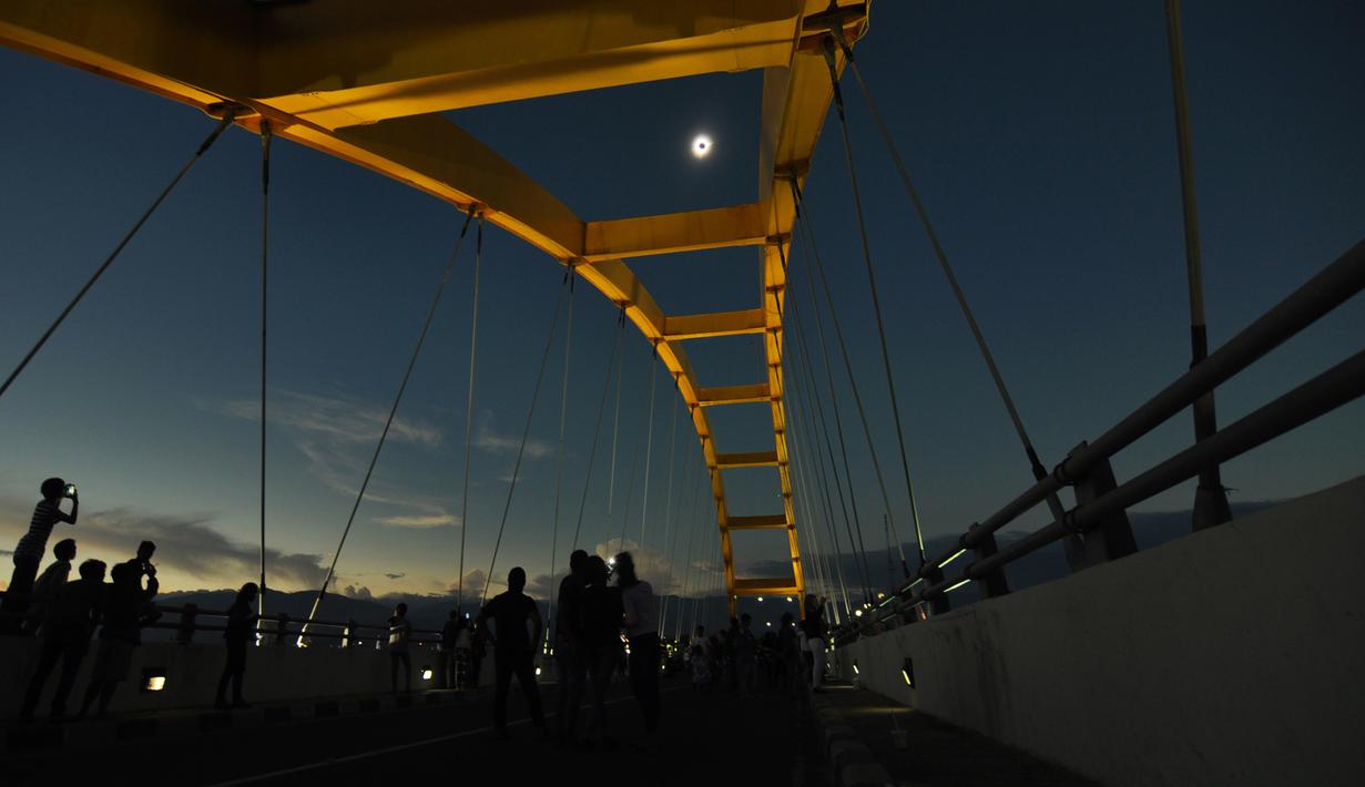Warga menyaksikan fase puncak Gerhana Matahari Total (GMT) yang dilihat dari Jembatan Teluk Palu, Sulawesi Tengah, Rabu (9/3/2015). (Nanang/AFP)