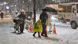 Orang-orang berjalan di trotoar yang tertutup salju di Distrik Nerima, Tokyo pada tanggal 5 Februari 2024. Hujan salju lebat melanda wilayah Tokyo dan sekitarnya. (Kazuhiro NOGI/AFP)