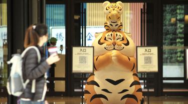 Warga berjalan melewati patung macan di depan pusat perbelanjaan jelang Tahun Baru Imlek di Taipei, Taiwan, 27 Januari 2022. Tahun Baru Imlek 2022 yang jatuh pada 1 Februari mendatang akan jadi tahun shio macan. (Sam Yeh/AFP)