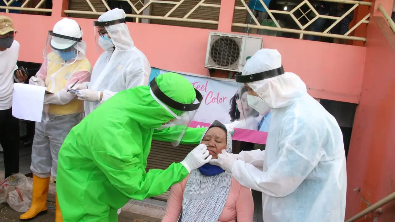 Petugas medis melakukan tes swab kepada seorang pedagang di pasar Bekasi