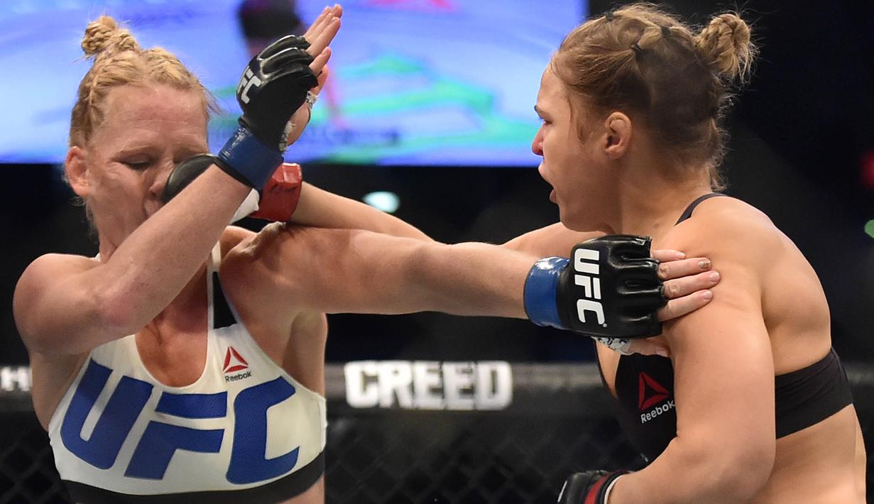 Pukulan dari Ronda Rousey, mendarat di wajah Holly Holm, pada pertarungan perebutan gelar juara kelas bantam UFC Women di Stadion Etihad, Melbourne, Minggu (15/11/2015). (AFP Photo/Paul Crock)