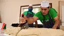 Koki dan relawan Muslim Aid memotong adonan saat membuat makanan ringan berbentuk segitiga, samosa raksasa, di Masjid London Timur, Inggris, Selasa (22/8). Camilan gurih dari India ini berisi 5 kg daging, sayuran dan rempah rempah. (BEN STANSALL/AFP)