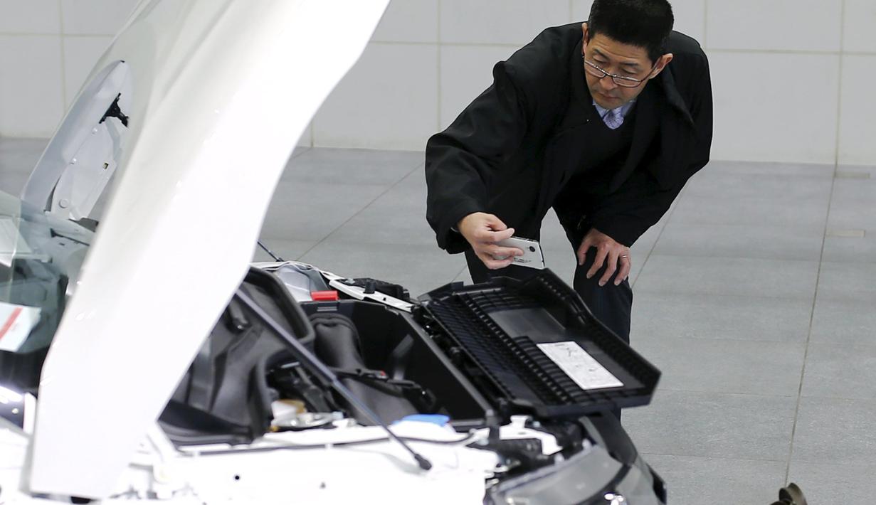 Pria mengambil gambar mesin mobil Honda S660 di Honda Motor Co di Tokyo, Jepang, (24/2). mobil sport mungil ini memiliki keunggulan dengan mengusung mesin kecil berkapasitas 660 cc turbo yang dikombinasikan penggerak roda depan. (REUTERS/Thomas Peter)