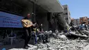 Seorang penyanyi Palestina tampil selama acara musik di puing-puing bangunan yang baru-baru ini hancur oleh serangan udara Israel di kota Gaza, Selasa (14/5/2019). Aksi tersebut untuk menyerukan pemboikotan terhadap Kontes Lagu Eurovision 2019 yang diselenggarakan di Israel. (REUTERS/Mohammed Salem)