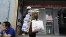 <p>Seorang wanita meninggalkan supermarket setelah membeli makanan dan perlengkapan rumah tangga di Beijing pada 25 April 2022. Kekhawatiran penguncian Covid memicu pembelian panik dan antrean panjang untuk pengujian massal di Beijing pada 25 April ketika otoritas China bergegas untuk membasmi wabah di ibu kota. (AFP/Noel Celis)</p>