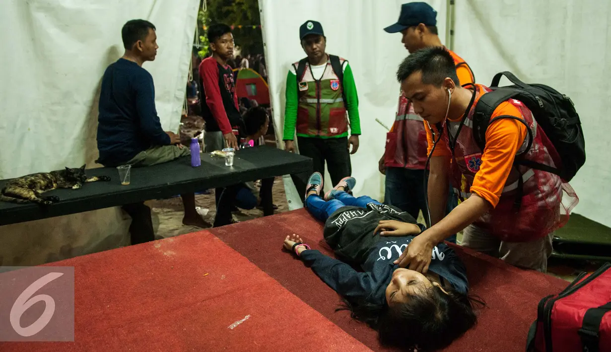 Pengunjung terlihat kelelahan usai menyaksikan atraksi kembang api diperiksa petugas medis di Pantai Lagoon , Ancol, Jakarta, Minggu (1/1). (Liputan6.com/Gempur M. Surya)