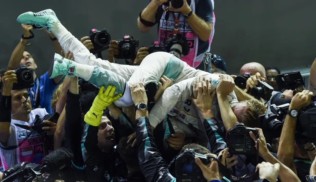 Pebalap Mercedes, Nico Rosberg, disambut kru Mercedes setelah menjuarai balapan F1 GP Singapura, Minggu (18/9/2016). (AFP/Anthony Wallace)
