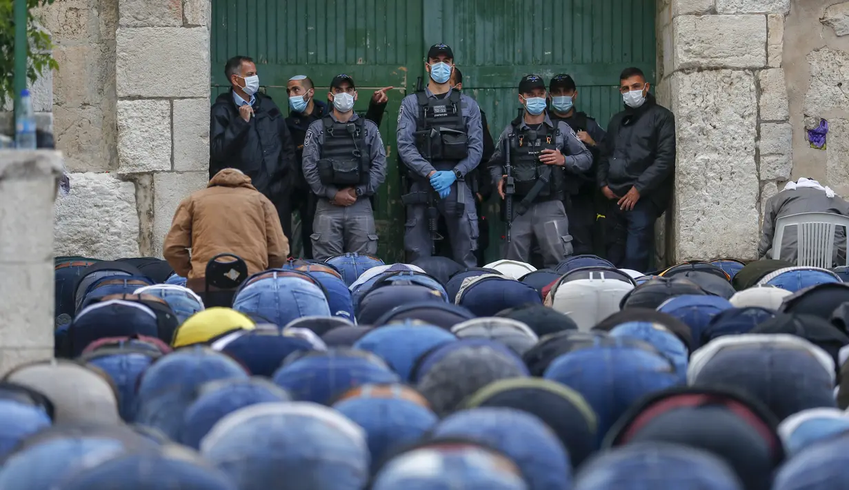 Pasukan keamanan Israel berjaga saat umat muslim Palestina melaksanakan salat Idul Fitri di luar Kompleks Masjidil Aqsa, Yerusalem, Minggu (24/5/2020). Masjidil Aqsa akan dibuka kembali setelah Idul Fitri karena pandemi virus corona COVID-19. (AHMAD GHARABLI/AFP)
