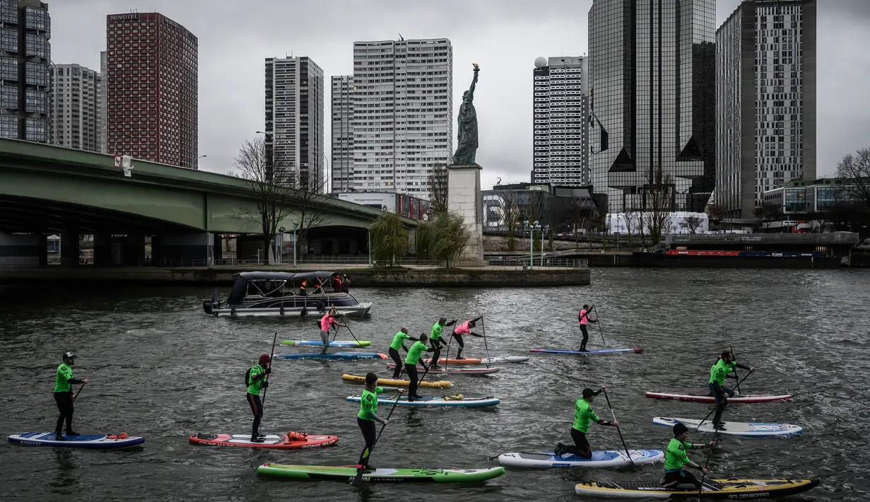 Peserta mengikuti lomba dayung sambil berdiri pada edisi ke-10 Nautic Paddle Race di Sungai Seine, Paris, Minggu (8/12/2019). Sekitar 1000 pesaing ikut serta dalam lomba sejauh 11 kilometer menyeberangi sungai Seine dengan pemandangan kota Paris. (Photo by Olivier MORIN / AFP)