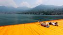 Dua wisatawan bersantai di atas seni instalasi 'The Floating Piers' sambil melihat landscape pemandangan bukti dan pegunungan di utara Italia karya Christo Vladimirov Javacheff di Danau Iseo, Italia utara, (24/6). (REUTERS/Stefano Rellandini)