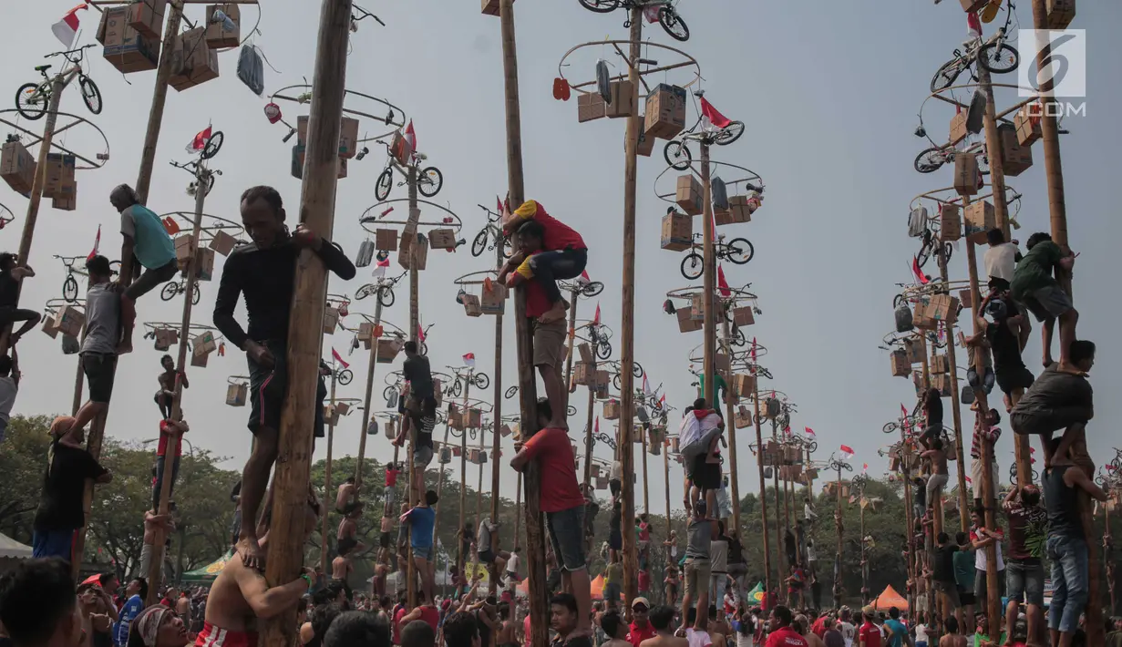 Warga mengikuti lomba Panjat Pinang Kolosal dalam rangka merayakan HUT ke-74 Kemerdekaan RI di Pantai Karnaval Ancol, Jakarta, Senin (17/8/2019). Sebanyak 174 batang pinang dengan beragam hadiah disediakan dalam lomba yang diikuti ratusan warga itu. (Liputan6.com/Faizal Fanani)