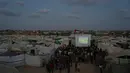 Warga Palestina menyaksikan siaran langsung pertandingan sepak bola Piala Dunia antara Spanyol dan Arab Saudi melalui layer lebar di Nuseirat, Jalur Gaza Tengah, Minggu 21 Juni 2026. (AP Photo/Abdel Kareem Hana)