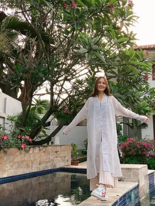 Kombinasi tunik berwarna putih dengan rok plisket warna krem plus sneakers warna putih memberikan kesan penampilan Pevita yang santai tapi menawan. (Instagram/pevpearce).