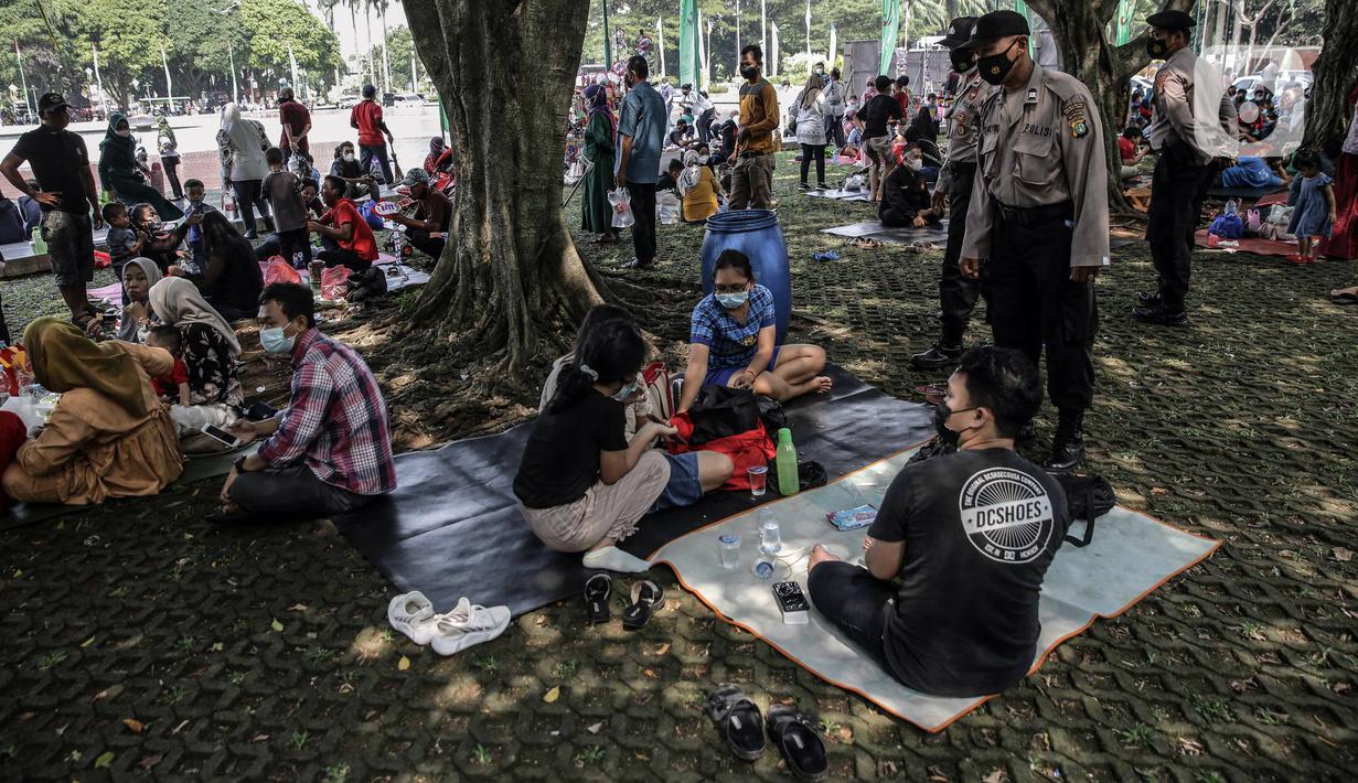 Polisi melakukan sosialisasi protokol kesehatan kepada para pengunjung yang berwisata di Taman Mini Indonesia Indah (TMII), Jakarta, Sabtu (15/5/2021). Banyak warga memilih berwisata ke TMII untuk menghabiskan waktu libur Lebaran. (Liputan6.com/Faizal Fanani)