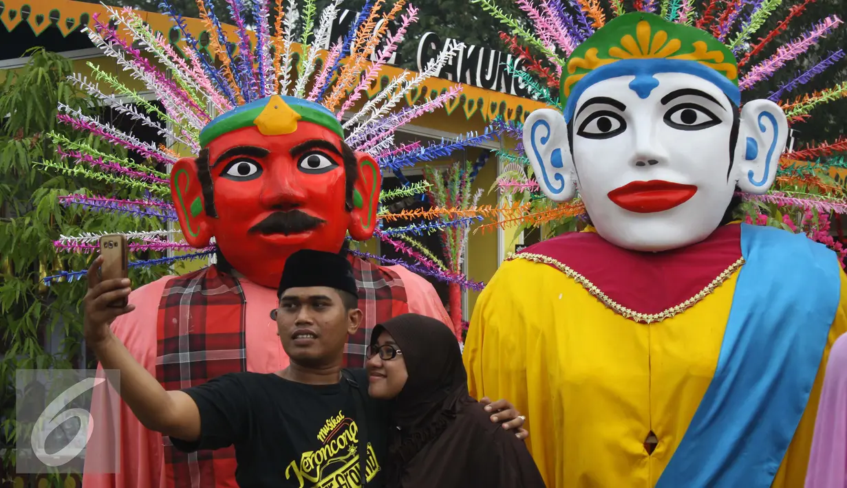 Pengunjung melakukan selfi didepan pajangan ondel-ondel dalam rangka Lebaran Betawi di Lapangan Banteng, Jakarta (22/08/15). Acara ini akan berlangsung pada tanggal 22-23 Agustus. (Liputan6.com/Gempur M Surya)