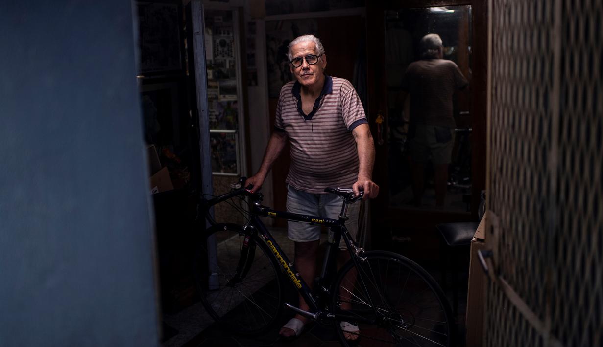 Raffaello Bianco, mekanik dan pecinta sepeda berpose di pintu masuk bengkel mekaniknya di ruang bawah tanah apartemennya di Turin, Italia, 7 Juli 2020. Raffaello Bianco adalah montir sepeda amatir yang sedang memperbaiki sepeda di garasi kecil dekat rumahnya. (MARCO BERTORELLO/AFP)