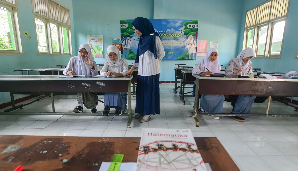 Seorang guru memberikan pelajaran matematika kepada empat murid baru kelas X di SMA 1 Muhammadiyah Depok,  Jawa Barat, Selasa (22/7/2025). (merdeka.com/Arie Basuki)