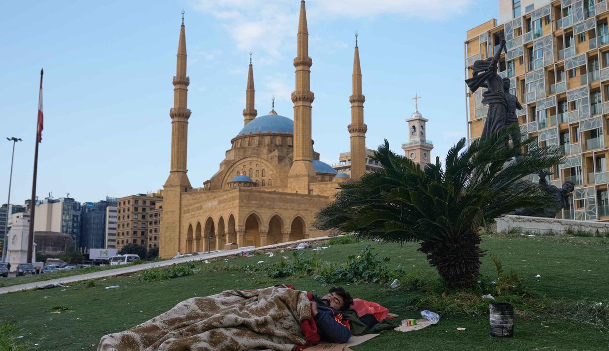 Seorang pria yang melarikan diri dari serangan udara Israel di Dahiyeh, pinggiran selatan Beirut, beristirahat di Lapangan Martir di pusat kota Beirut, Lebanon, Sabtu 7 Maret 2026. Untuk menghindari serangan udara Israel yang menyasar kawasan permukiman, terutama di wilayah Dahiyeh, ratusan warga Beirut, Lebanon, memilih tidur di trotoar, taman, mobil, dan tepi laut. (AP Photo/Bilal Hussein)