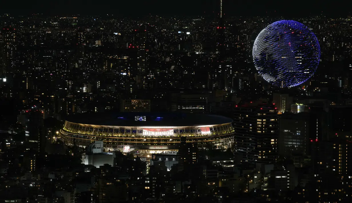 Drone yang membuat formasi menyerupai bola dunia menghiasi langit kota Tokyo saat upacara pembukaan Olimpiade Tokyo 2020, Jumat (23/7/2021). (Foto: AP/Eugene Hoshiko)