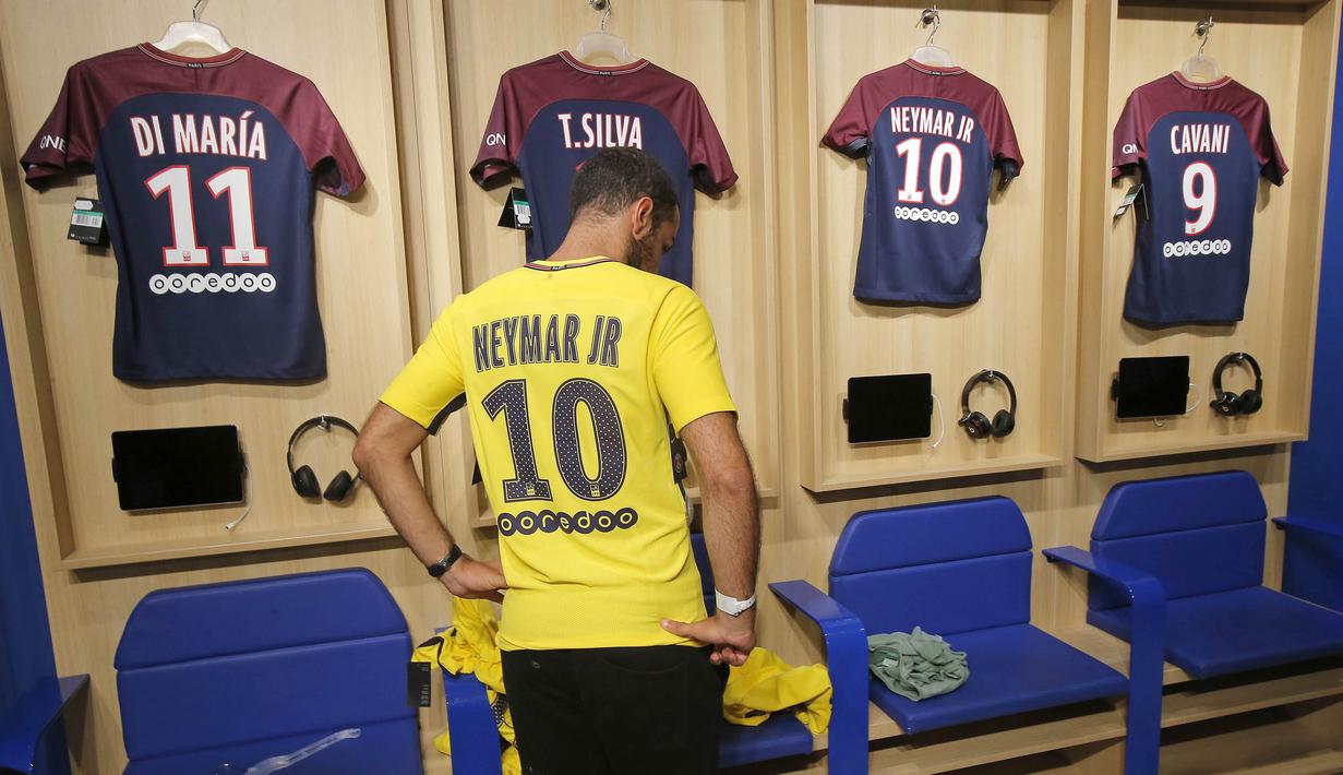 Seorang fans mencoba jersey pemain baru Paris Saint Germain, Neymar Jr, di toko merchandise di Paris, Jumat (4/8/2017). Setelah resmi bergabung dengan Paris Saint Germain, jersey Neymar Jr langsung diburu suporter klub Ibu kota. (AP/Michel Euler)