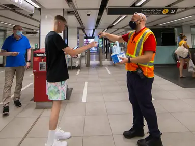 Seorang staf Toronto Transit Commission (TTC) membagikan masker baru kepada penumpang di stasiun kereta bawah tanah di Toronto, Kanada, pada 2 Juli 2020. TTC mewajibkan para pengguna layanan kereta memakai masker atau penutup wajah mulai Kamis (2/7) karena pandemi COVID-19. (Xinhua/Zou Zheng)