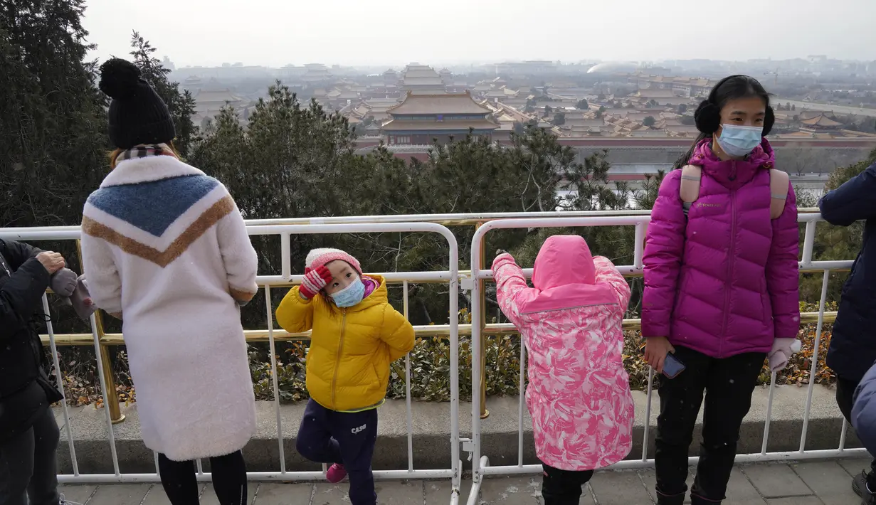 Pengunjung menikmati pemandangan menghadap Kota Terlarang dari taman Jingshan pada hari bersalju di Beijing, China, Selasa (19/1/2021). China sekarang berurusan dengan pandemi virus corona di timur lautnya yang dingin, mendorong penguncian ketat dan pembatasan perjalanan. (AP Photo/Ng Han Guan)