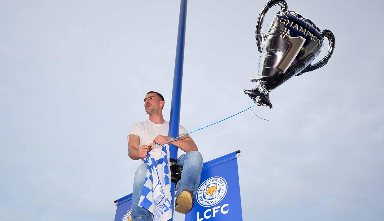 Seorang fans Leicester City rela memanjat tiang lampu jalan saat merayakan titel juara Liga Inggris 2015-2016 di Areal Stadion King Power (7/5/2016). (AFP/Glyn Kirk)