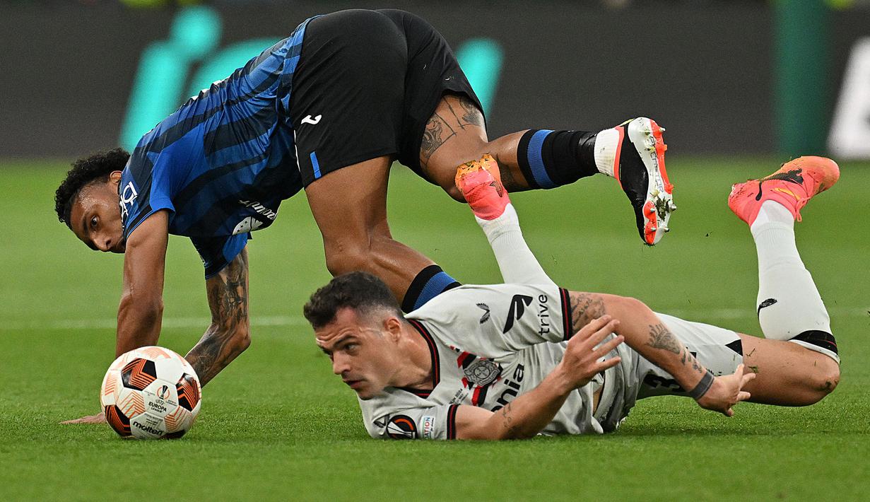 Pemain Bayer Leverkusen, Granit Xhaka (kanan) terjatuh saat berebut bola dengan pemain Atalanta, Ederson pada laga final Liga Europa 2023/2024 yang berlangsung di Dublin Arena, Irlandia, Kamis (23/05/2024) dini hari WIB. (AFP/Glyn Kirk)
