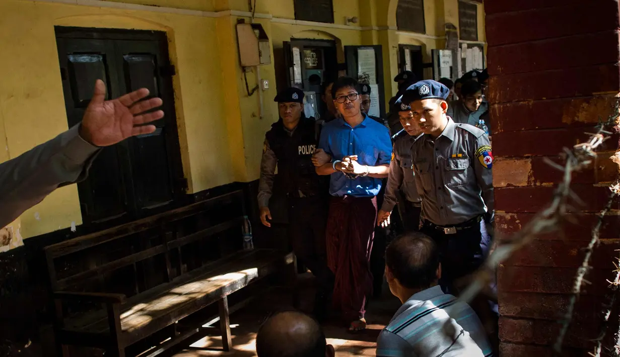 Wartawan Reuters Wa Lone (tengah) dikawal oleh polisi setelah menjalani sidang di Yangon (10/1). Polisi Myanmar resmi mengajukan tuntutan terhadap dua wartawan Reuters yang dituduh membocorkan rahasia negara. (AFP Photo/Ye Aung Thu)
