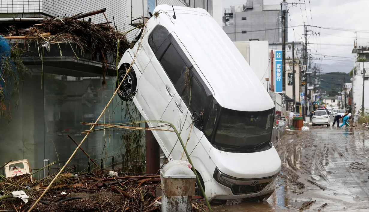 Sebuah mobil bersandar pada bangunan menyusul hujan lebat di Hitoyoshi, prefektur Kumamoto, Jepang, Senin (6/7/2020). Banjir di wilayah Kumamoto yang memicu tanah longsor ini telah menghancurkan ratusan rumah dan kendaraan serta membuat jembatan antar kota terputus. (Yuki Sato/Kyodo News via AP)