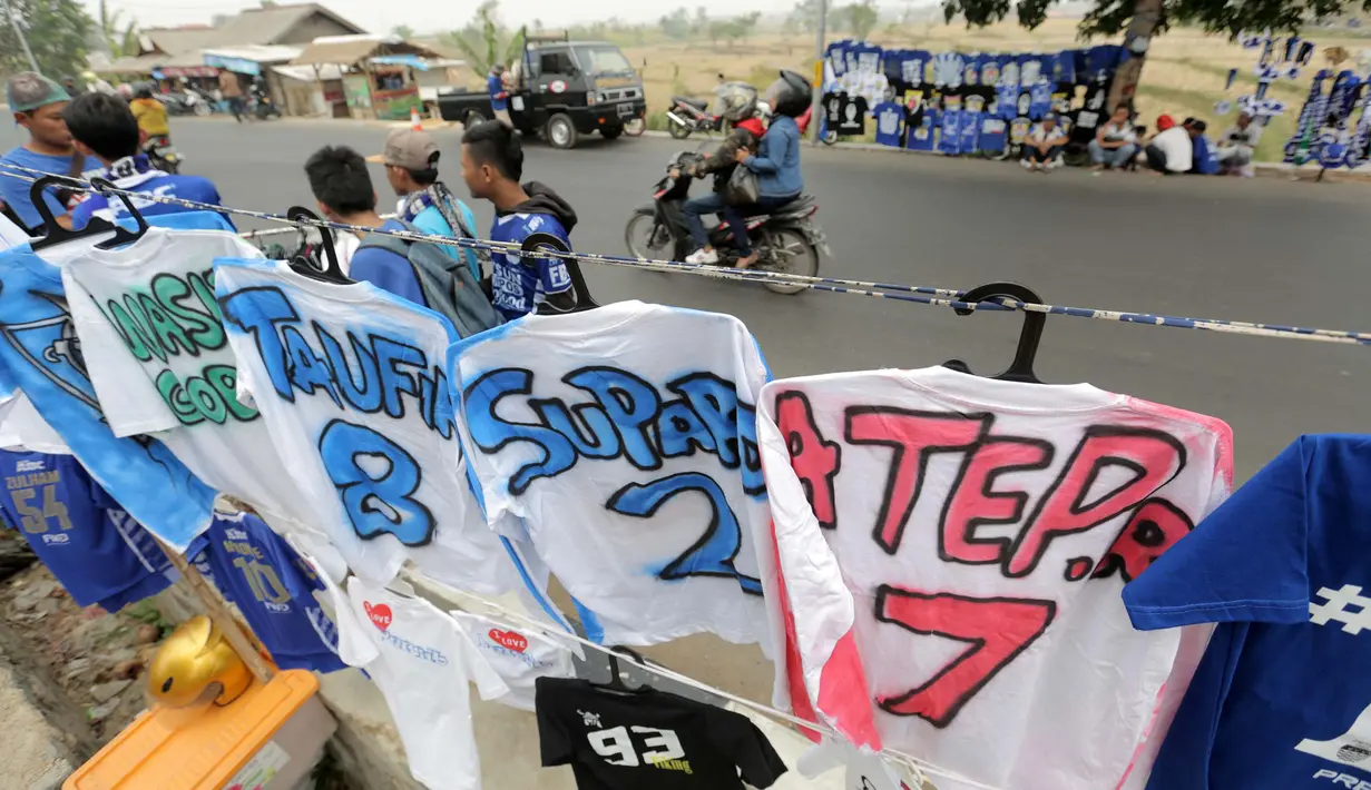 Seorang pedagang atribut Persib melayani pembeli  Jersey dari airbrush di Stadion Si Jalak Harupat, Bandung, Sabtu (24/10/2015). (Bola.com / Nicklas Hanoatubun)