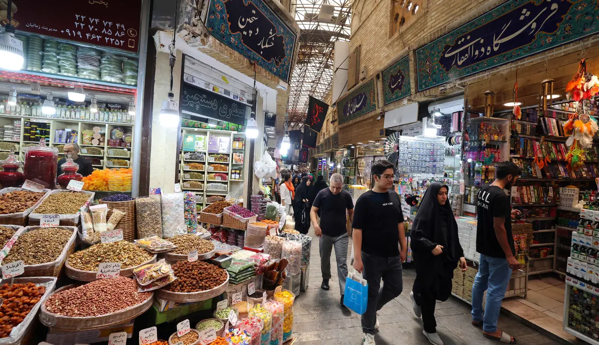 Orang-orang berjalan melewati toko-toko di Tajrish Bazaar, ibu kota Iran, Teheran, pada 30 Juni 2025. (ATTA KENARE/AFP)
