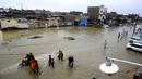 Warga melintasi jalan yang banjir setelah hujan deras di Karachi, Pakistan, Selasa (30/7/2019). Hujan deras terjadi pada hari Senin dan berlanjut pada hari Selasa dan air limbah membanjiri sebagian besar jalan di Karachi, ibukota provinsi Sindh selatan. (AP/Photo/Fareed Khan)
