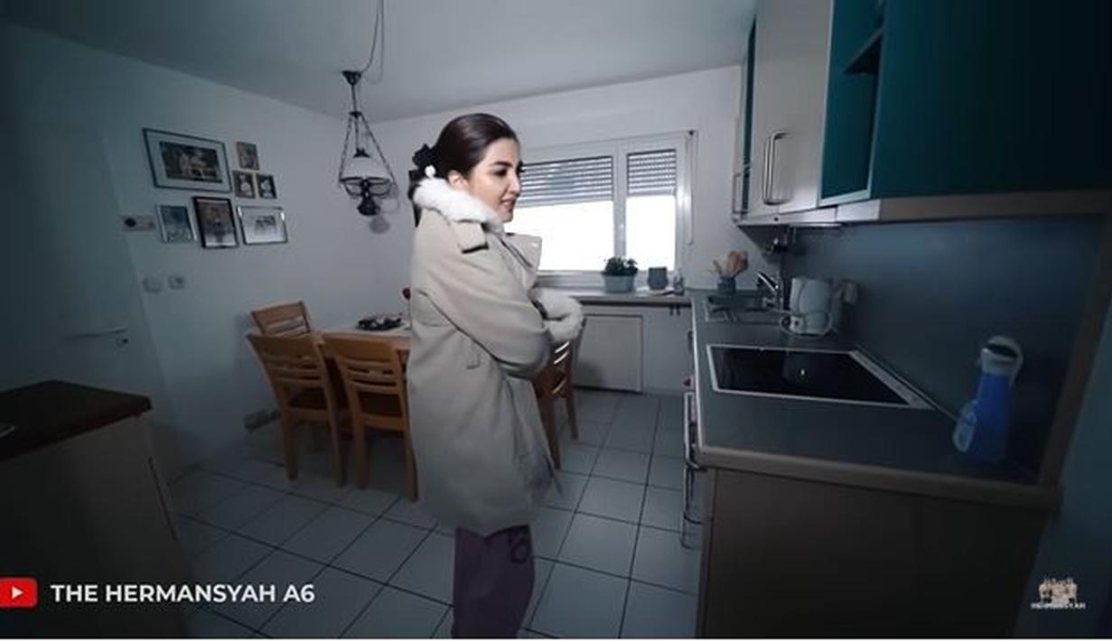 Dapurnya juga tampak bersih dan rapi. Interiornya didominasi oleh warna putih, sehingga tampak begitu elegan. Di tengah ruangan dapur juga terdapat kursi dan meja makan yang terbuat dari kayu. Di salah satu dinding juga tampak ada sejumlah foto yang ditempel. (Liputan6.com/YouTube/The Hermansyah A6)