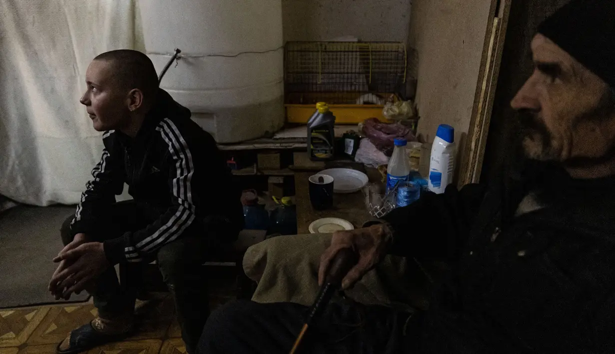 Penduduk setempat menunggu di ruang bawah tanah di bawah pemadaman listrik di kota Bakhmut, Ukraina timur (22/12/2022). Mereka mencari perlindungan karena penembakan hebat oleh pasukan Rusia. (AFP/Sameer Al-Doumy)