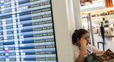Seorang wanita beristirahat di samping papan informasi penerbangan di Terminal Internasional Bandara Haneda setelah penerbangan dibatalkan atau ditunda karena badai tropis Jangmi di Tokyo, Jepang, Rabu 3 Juni 2026. (Andrew CAALLERO-REYNOLDS/AFP)
