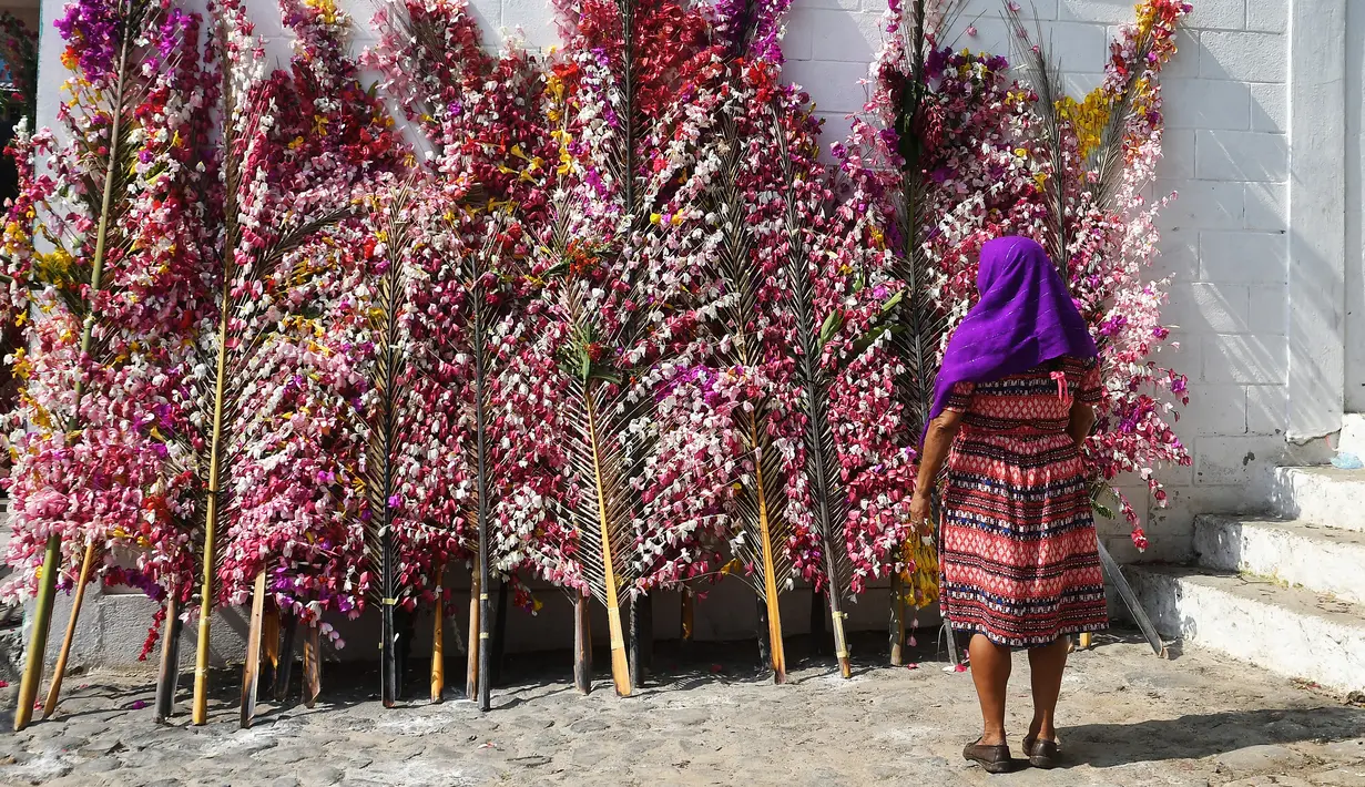 Seorang wanita melihat daun kelapa yang dihias bunga saat festival tahunan Panchimalco Flower and Palm Festival di Panchimalco, San Salvador (6/5). (AFP/Marvin Recinos)