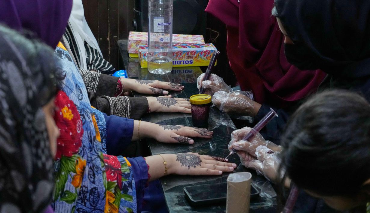 Melukis henna merupakan tradisi yang cukup popular di Pakistan untuk mempercantik diri menjelang Hari Raya Idul Fitri. Tampak dalam foto, para ahli kecantikan melukis 'Henna' tradisional di tangan pelanggan untuk perayaan Idul Fitri, yang menandai berakhirnya bulan suci Ramadan, di Rawalpindi, Pakistan, Rabu, 18 Maret 2026. (AP Photo/Anjum Naveed)