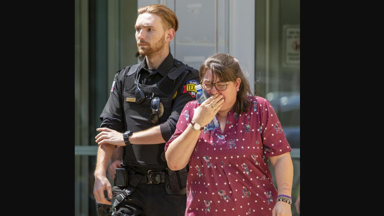 Seorang wanita menangis di dekat polisi usai terjadi penembakan di Robb Elementary School yang berlokasi di Texas. 14 anak tewas.